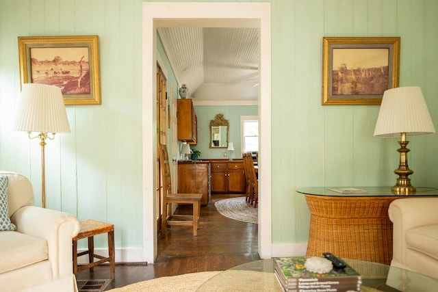 corridor with lofted ceiling, wooden walls, dark wood finished floors, and baseboards