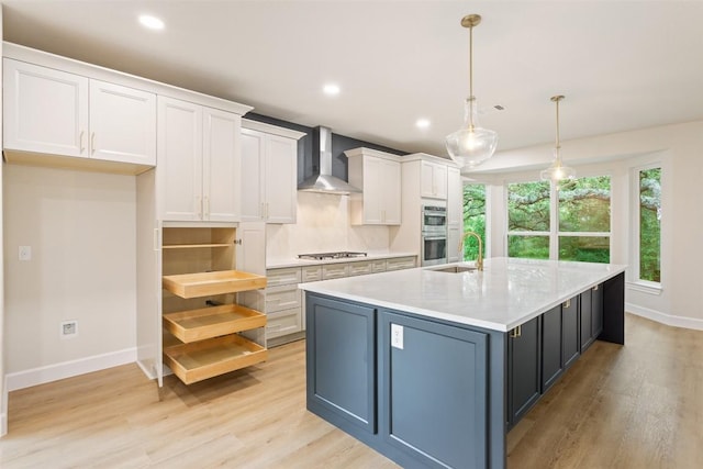 204 San Saba Dr, Georgetown, TX 78633 - kitchen featuring wall chimney range hood, baseboards, stainless steel appliances, white cabinetry, and an island with sink