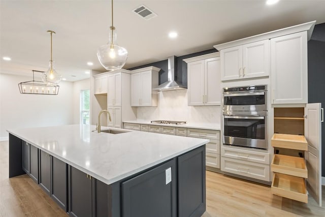 204 San Saba Dr, Georgetown, TX 78633 - kitchen with visible vents, wall chimney exhaust hood, a sink, light wood-style flooring, and appliances with stainless steel finishes
