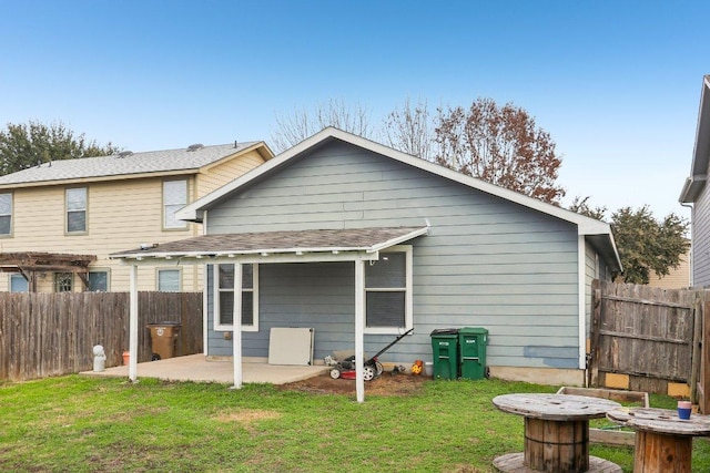 rear view of house with fence, a yard, and a patio area