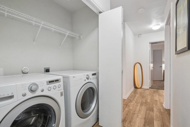 washroom with laundry area, baseboards, light wood-style flooring, and washing machine and dryer