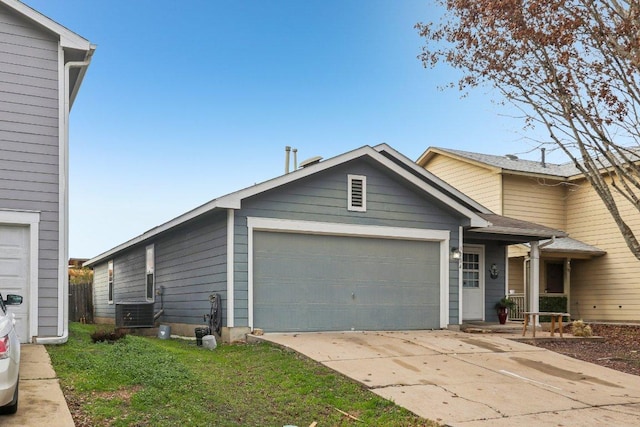 view of front of home featuring driveway, central AC unit, and a garage