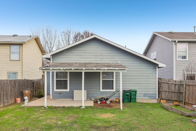 rear view of property featuring fence, a patio, a yard, and a garden