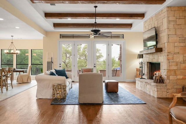 living area with beam ceiling, wood finished floors, ceiling fan with notable chandelier, and a fireplace