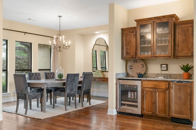 bar with a sink, a notable chandelier, dark wood-type flooring, pendant lighting, and beverage cooler