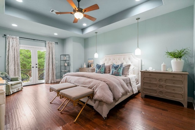 bedroom with dark wood-type flooring, a tray ceiling, access to exterior, visible vents, and french doors
