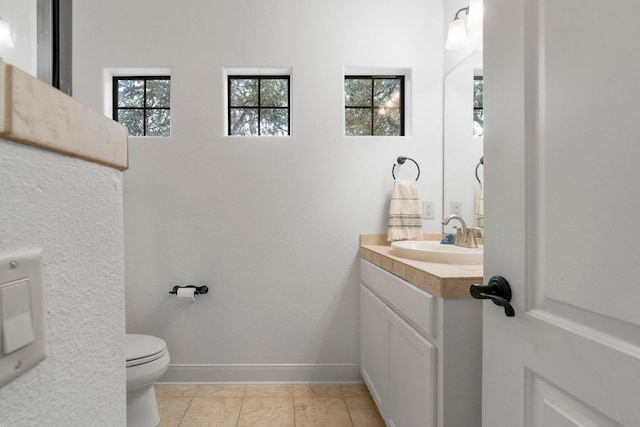 half bathroom with vanity, toilet, and baseboards