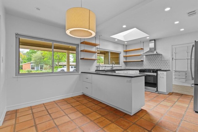 kitchen featuring black stove, open shelves, wall chimney exhaust hood, dark countertops, and a skylight