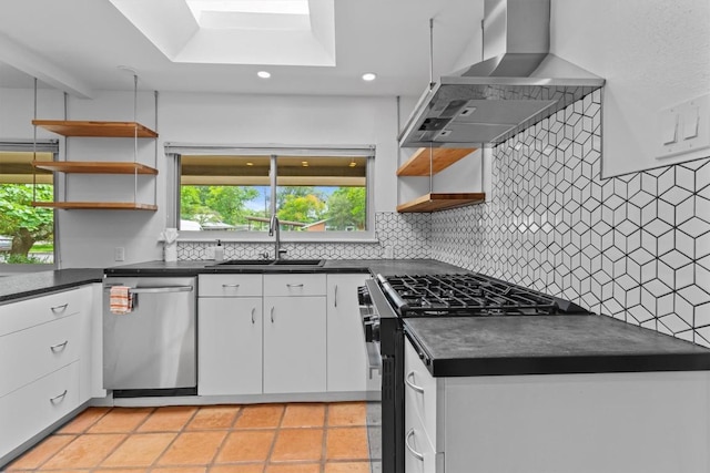 kitchen with wall chimney range hood, open shelves, a sink, dark countertops, and stainless steel appliances