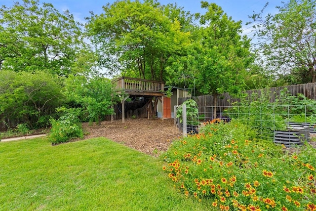 view of yard featuring fence, a vegetable garden, and a wooden deck