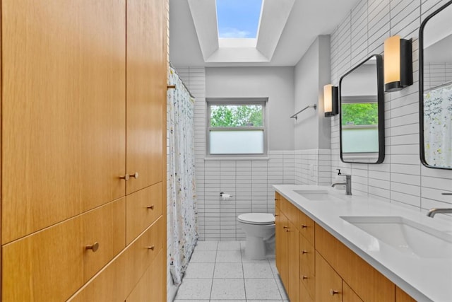 full bath with toilet, tile walls, a sink, and tile patterned floors