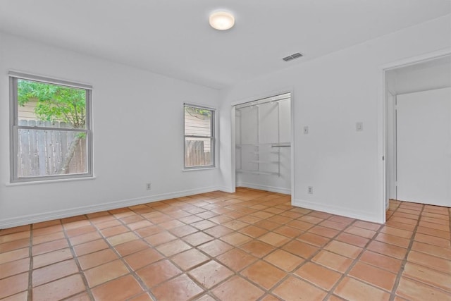 unfurnished bedroom with baseboards, visible vents, light tile patterned floors, and a closet