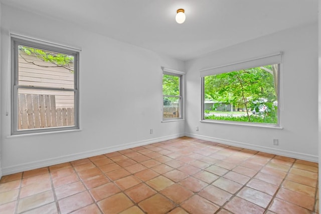 spare room featuring light tile patterned flooring and baseboards