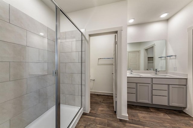 bathroom featuring wood finished floors, a stall shower, and a sink