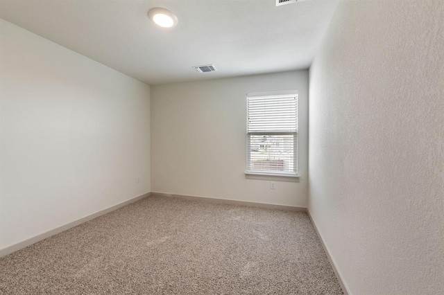 empty room featuring visible vents, light colored carpet, and baseboards