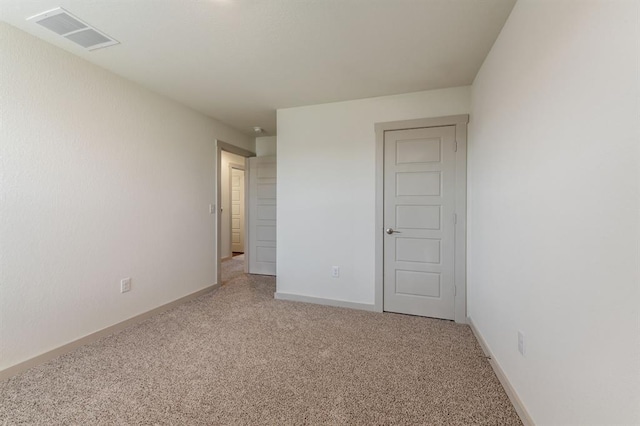 empty room featuring visible vents, light colored carpet, and baseboards