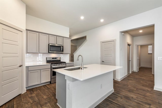 kitchen featuring gray cabinetry, a sink, appliances with stainless steel finishes, and dark wood finished floors