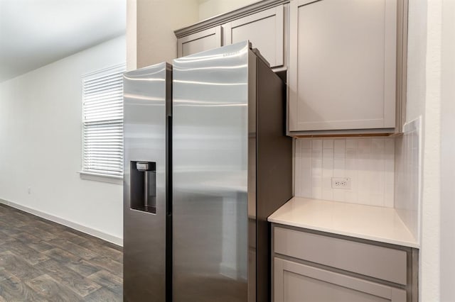 kitchen with tasteful backsplash, light countertops, dark wood finished floors, stainless steel fridge, and gray cabinets