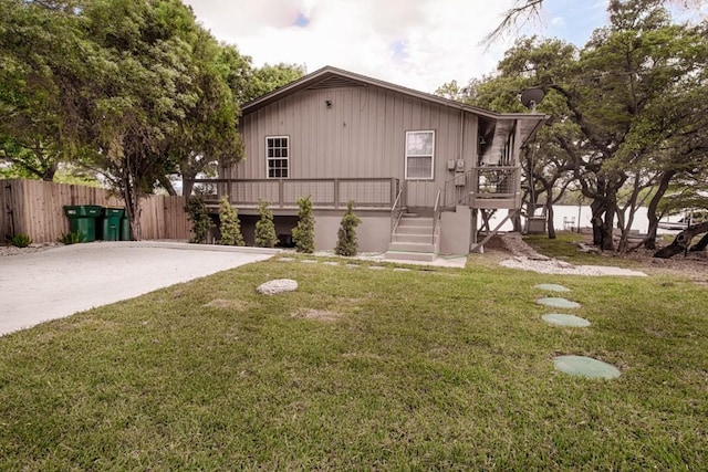 chalet / cabin featuring stairs, a wooden deck, fence, and a front yard