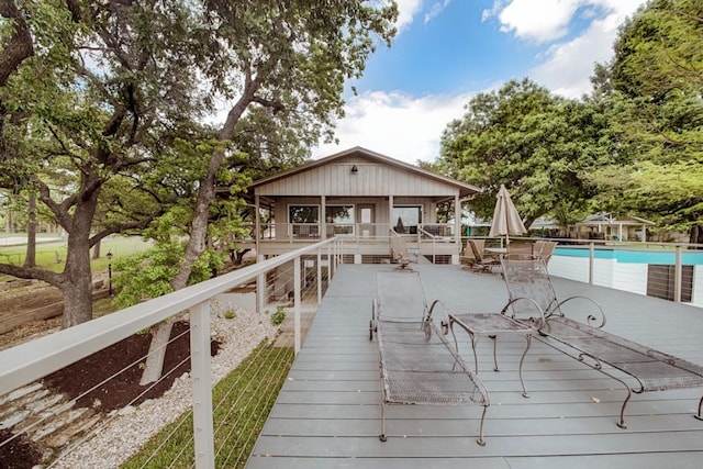 back of house with a wooden deck, a patio area, and an outdoor pool