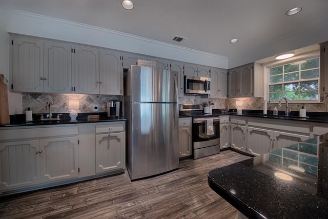 kitchen with visible vents, crown molding, dark wood-style flooring, a sink, and stainless steel appliances