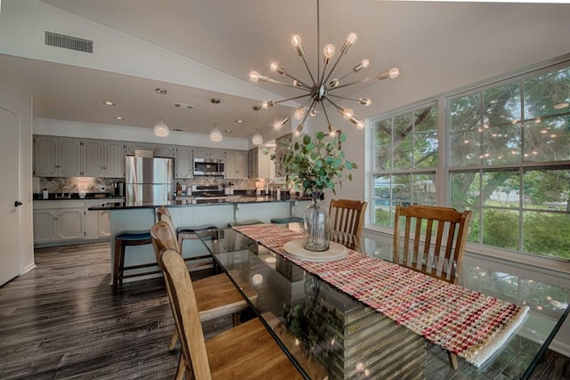 dining room with vaulted ceiling, dark wood-type flooring, a chandelier, and visible vents