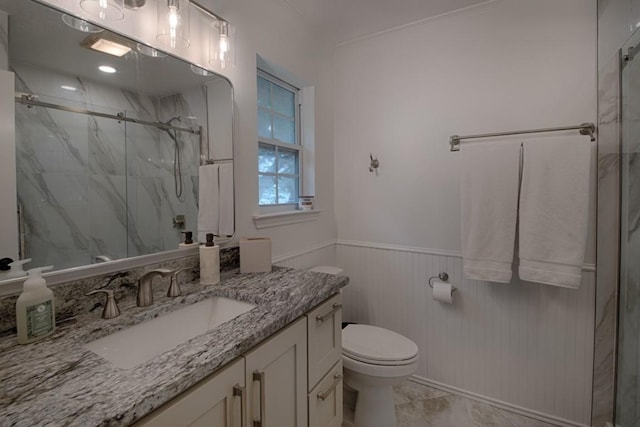 full bathroom with vanity, toilet, a marble finish shower, marble finish floor, and a wainscoted wall