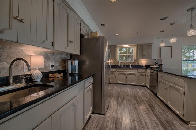 kitchen with backsplash, visible vents, a sink, a peninsula, and stainless steel appliances