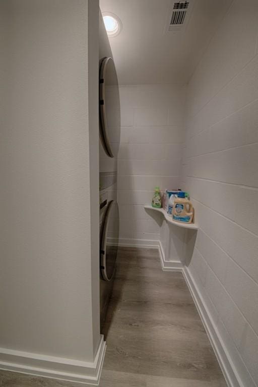 washroom with wood finished floors, laundry area, stacked washer / dryer, and visible vents