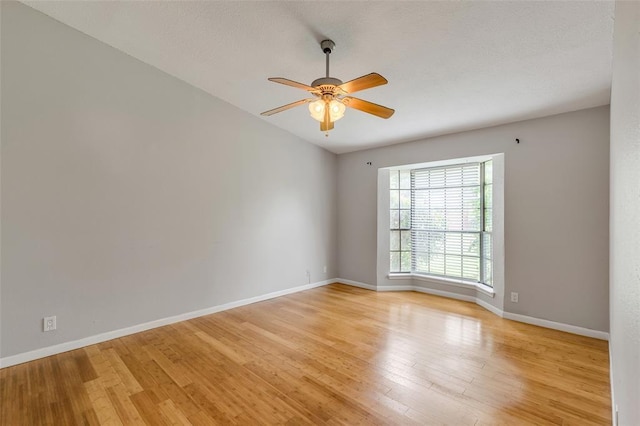 empty room featuring a ceiling fan, light wood-style floors, and baseboards