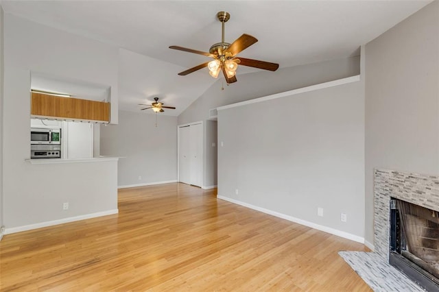 unfurnished living room with a fireplace, a ceiling fan, visible vents, light wood-style flooring, and lofted ceiling
