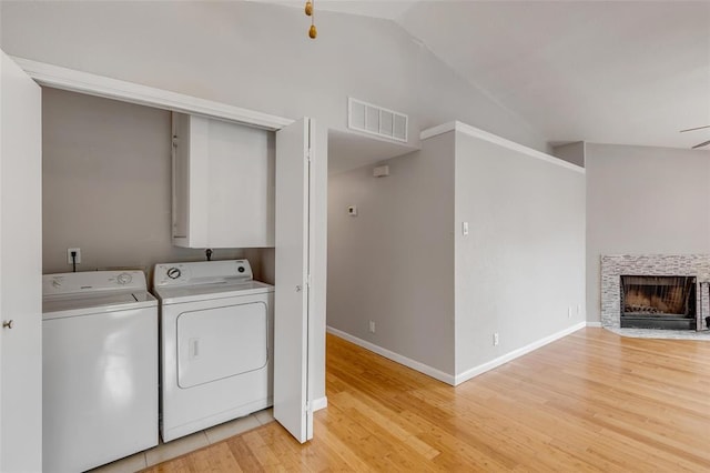 laundry area with independent washer and dryer, laundry area, light wood-type flooring, visible vents, and baseboards