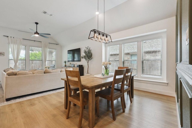 dining space featuring light wood-type flooring, vaulted ceiling, a ceiling fan, and baseboards