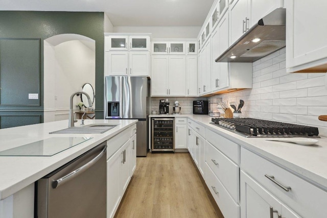 kitchen featuring wine cooler, under cabinet range hood, stainless steel appliances, a sink, and light countertops