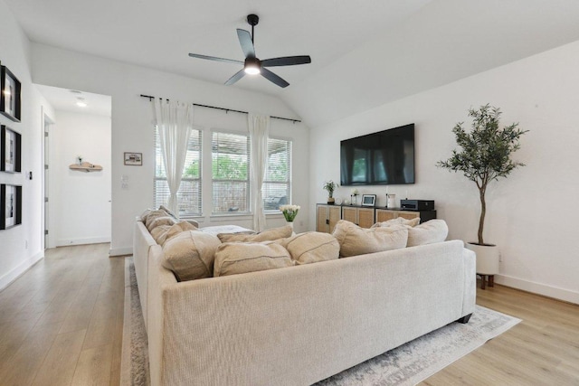 living area with a ceiling fan, light wood-type flooring, baseboards, and lofted ceiling