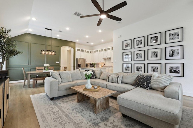 living room featuring light wood-style flooring, a ceiling fan, arched walkways, lofted ceiling, and recessed lighting