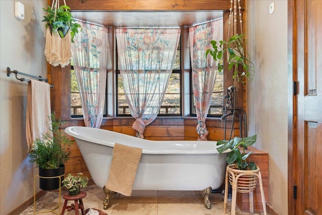 full bath with baseboards, a textured wall, a soaking tub, and tile patterned flooring
