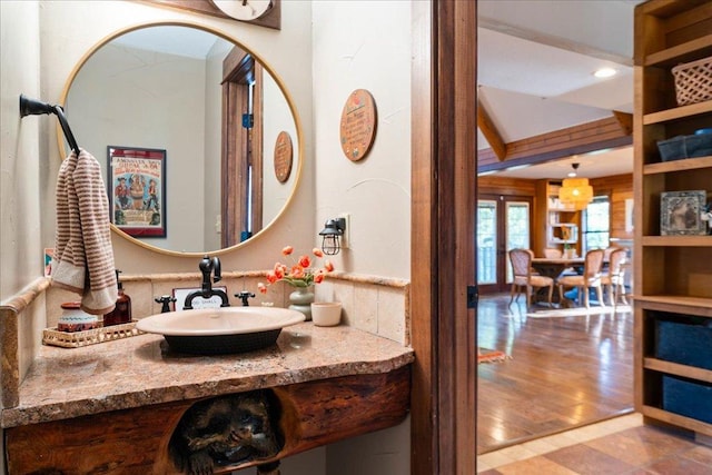 bathroom featuring french doors, a sink, and wood finished floors