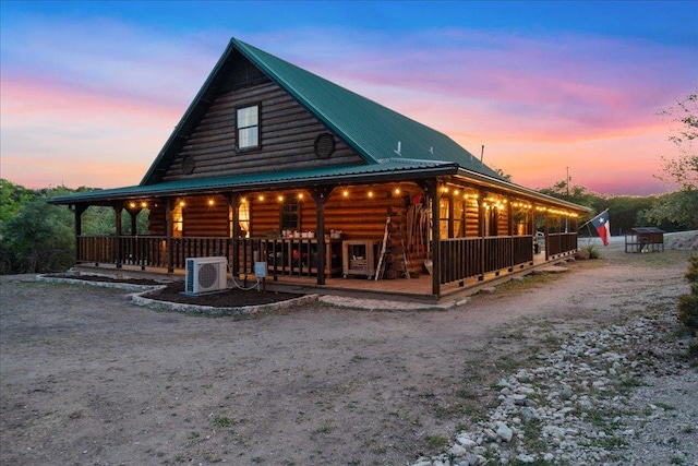 view of front of house featuring covered porch, ac unit, metal roof, and log siding