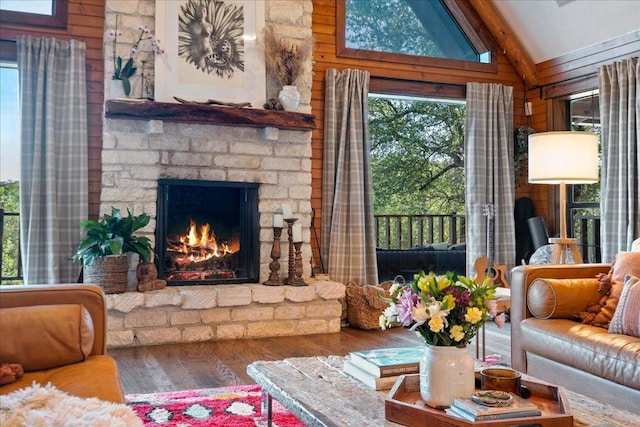 living area with wood walls, lofted ceiling with beams, wood finished floors, and a fireplace
