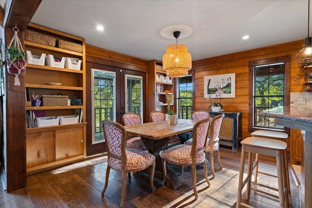 dining room with wood walls, a healthy amount of sunlight, and hardwood / wood-style floors
