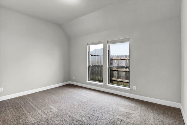 carpeted empty room featuring baseboards and lofted ceiling