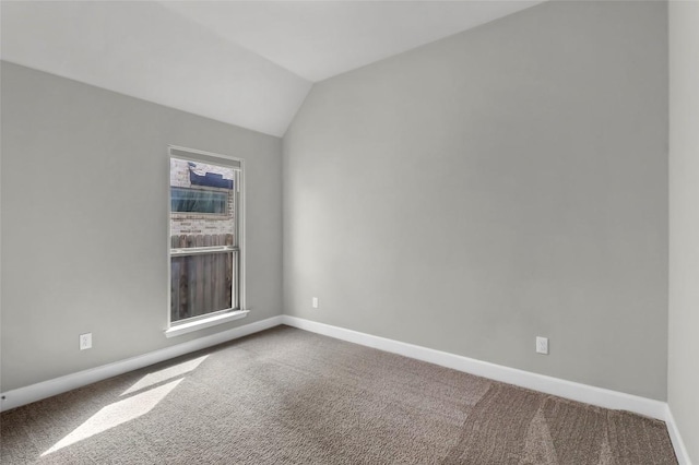 carpeted empty room featuring baseboards and lofted ceiling