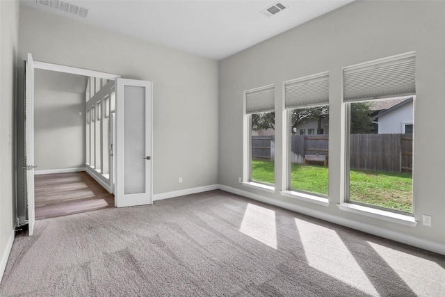 empty room with visible vents, a healthy amount of sunlight, and carpet