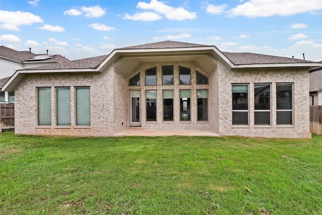 rear view of house with fence, a patio, a yard, and brick siding