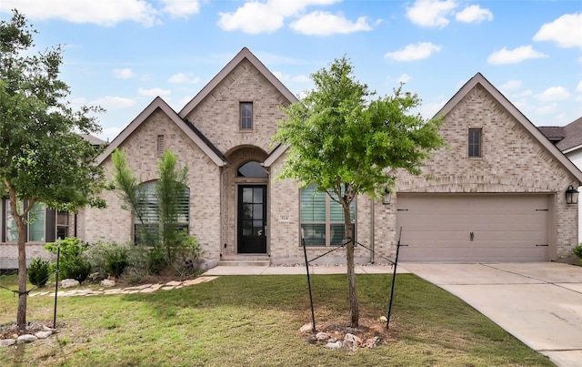 french country home featuring concrete driveway, brick siding, a garage, and a front lawn