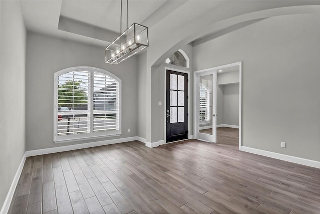 entryway with dark wood-type flooring, arched walkways, baseboards, and a notable chandelier