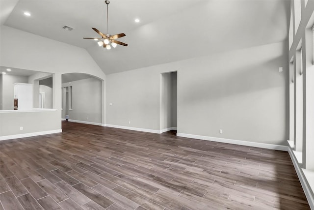 unfurnished living room featuring arched walkways, ceiling fan, dark wood finished floors, and baseboards