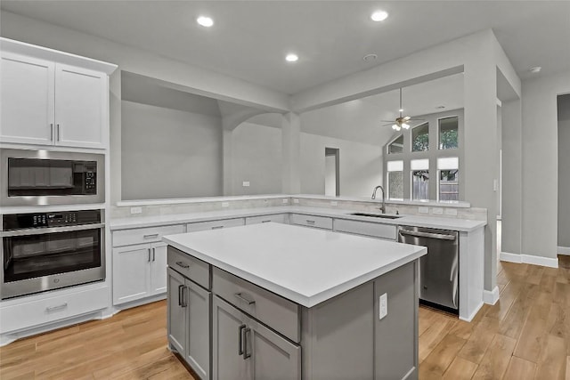 kitchen featuring a ceiling fan, a center island, light countertops, a sink, and stainless steel appliances