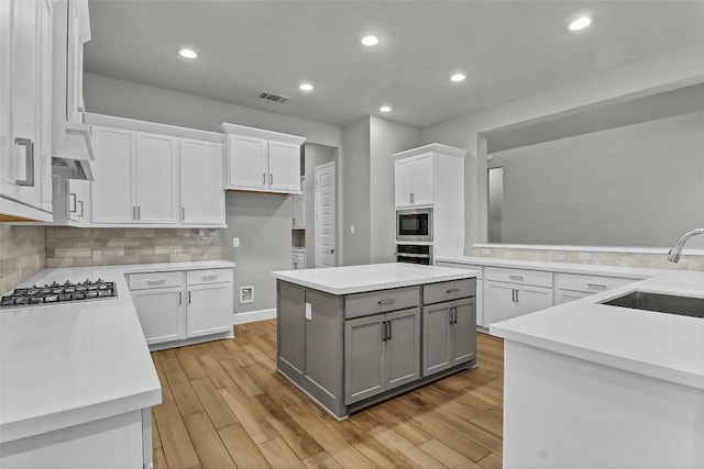 kitchen with appliances with stainless steel finishes, a sink, light countertops, gray cabinets, and visible vents